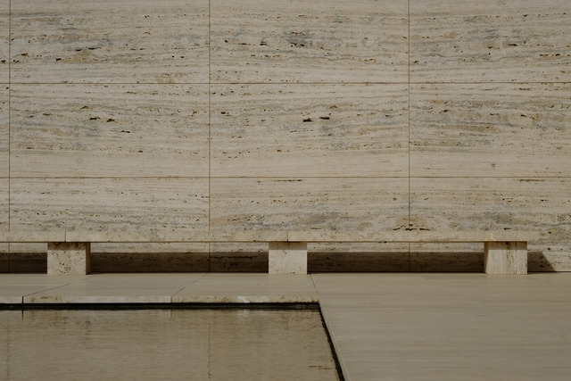 Travertine wall and bench beside a still reflecting pool