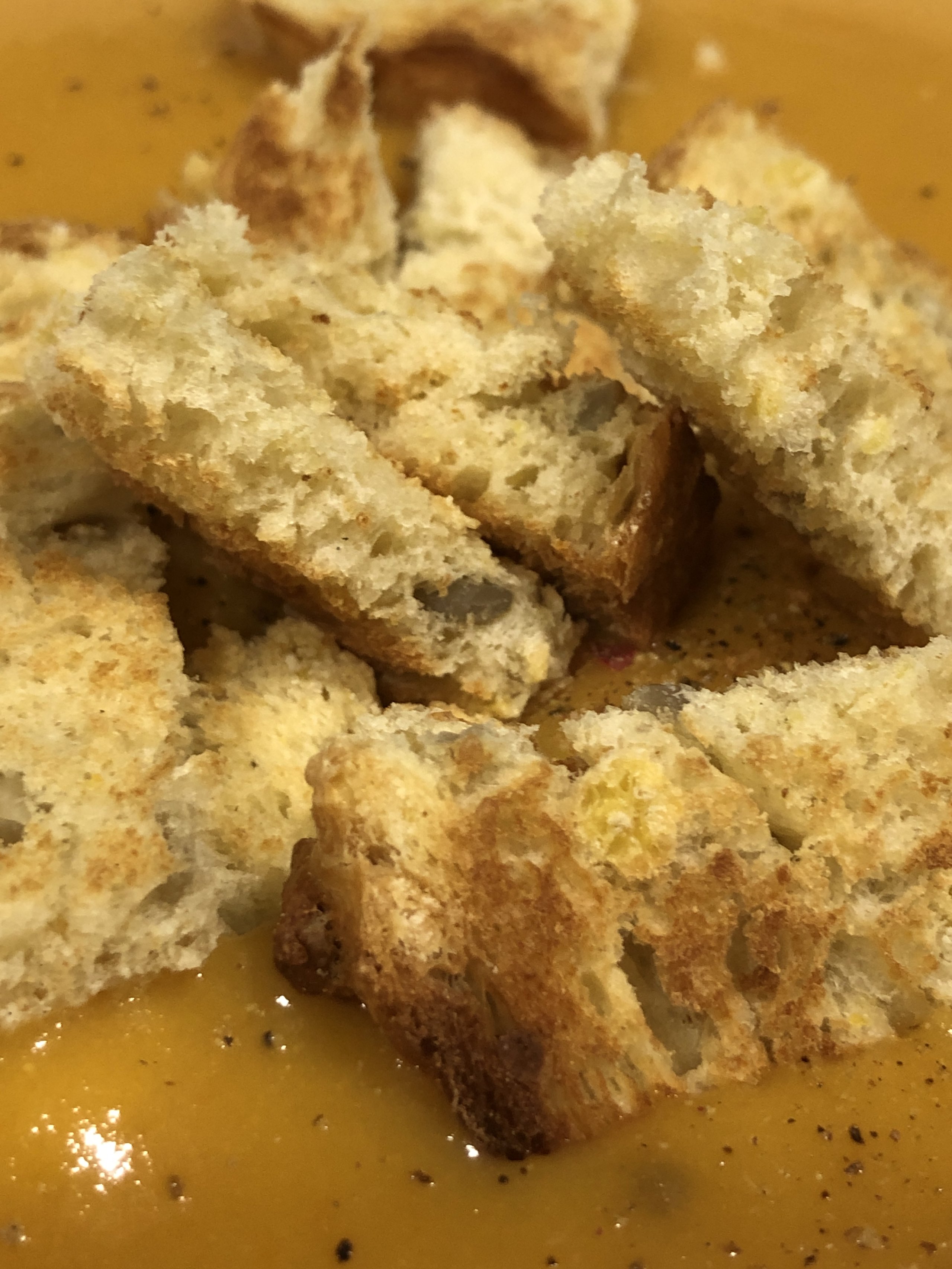 Toasted croutons piled on golden squash soup