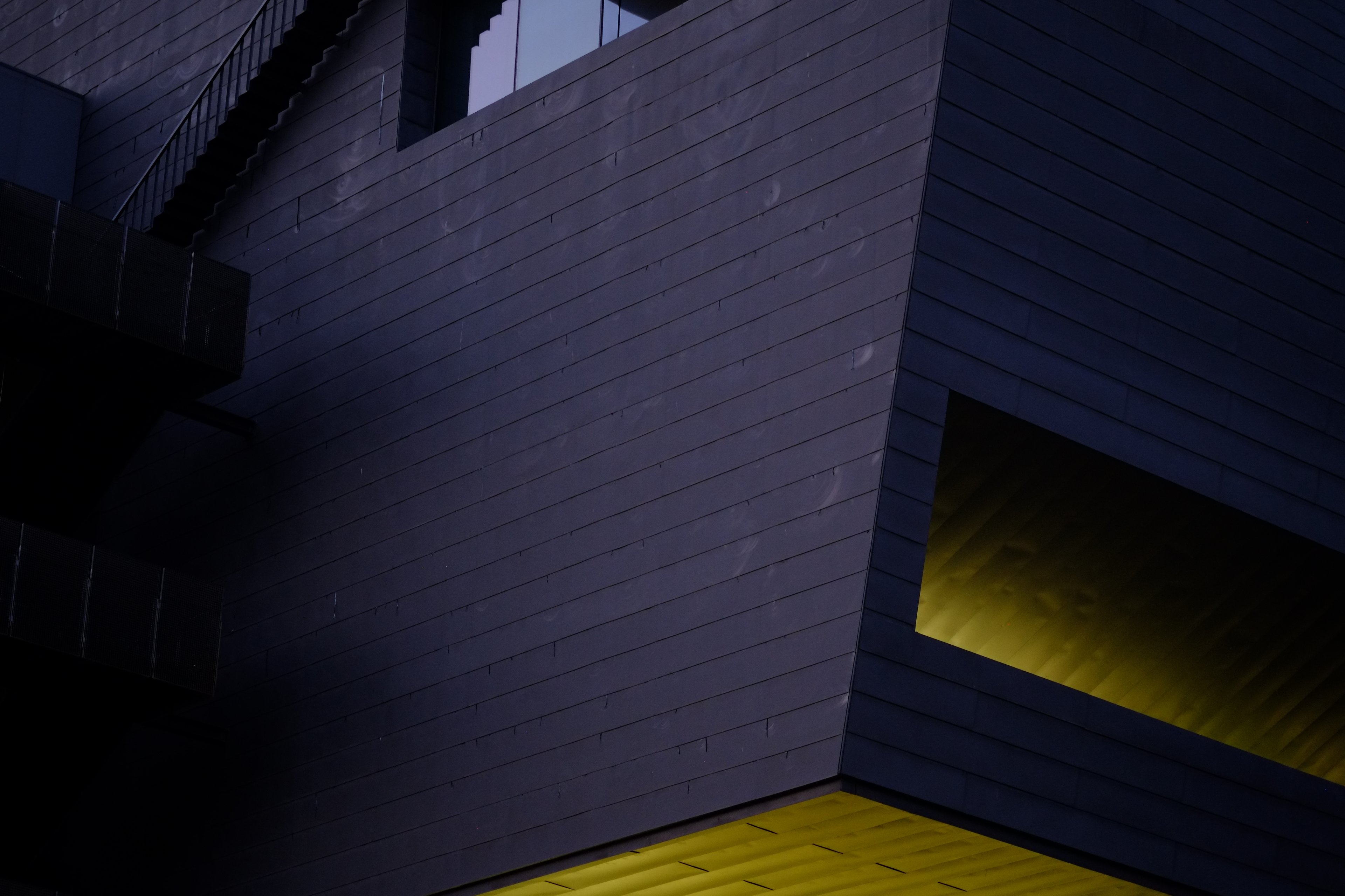 A dark tiled corner at dusk, lit yellow from beneath