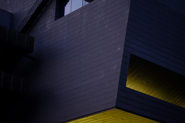 A dark tiled corner at dusk, lit yellow from beneath