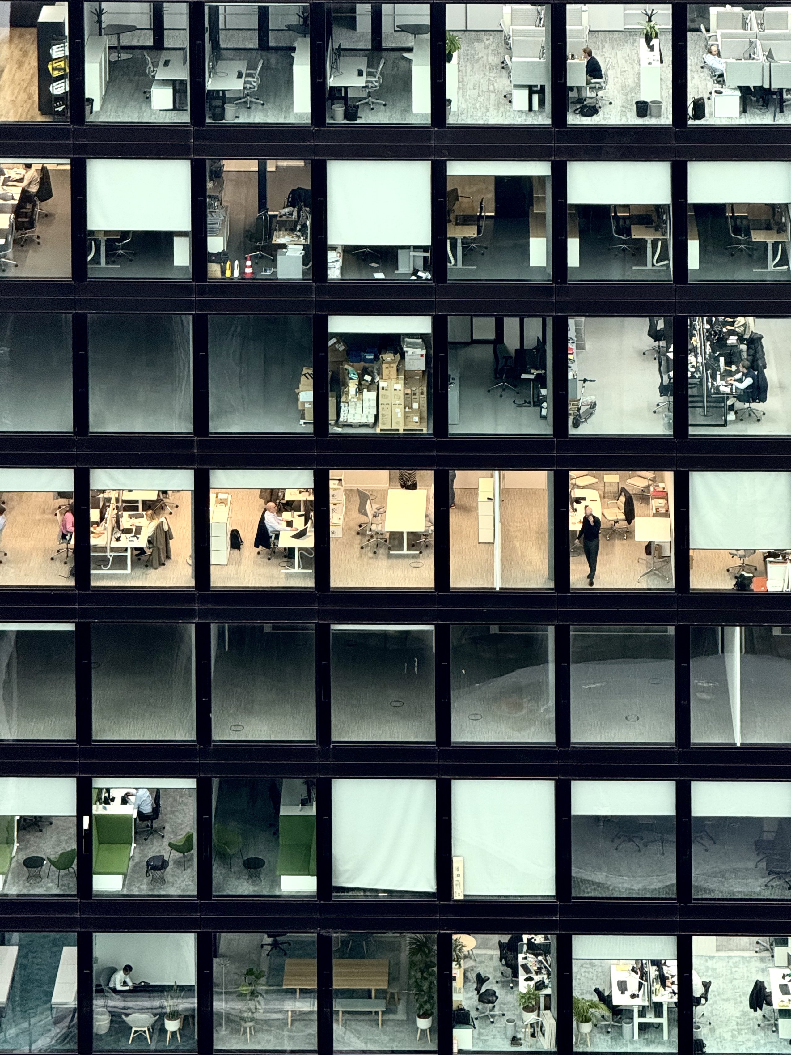 A grid of office windows at dusk, a few floors still working