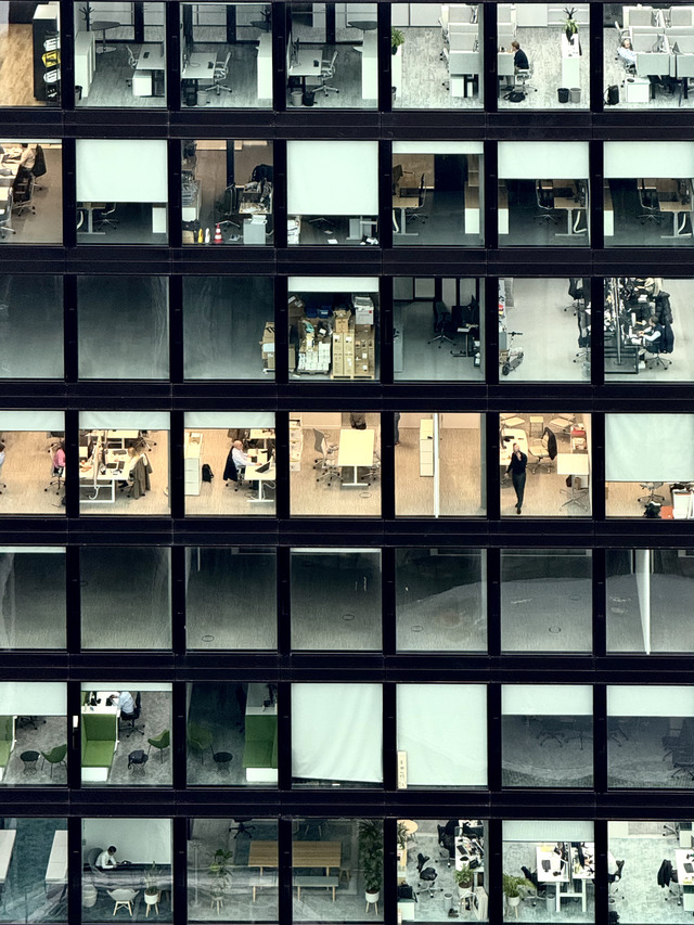 A grid of office windows at dusk, a few floors still working