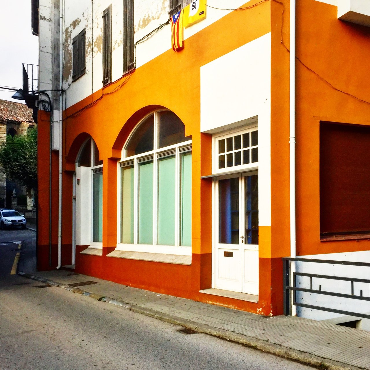 Bright orange building front with arched windows and a flag above