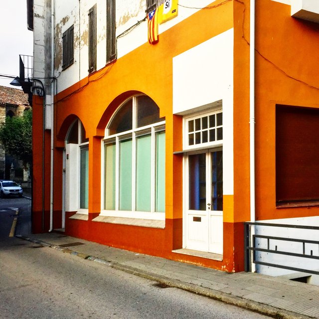 Bright orange building front with arched windows and a flag above