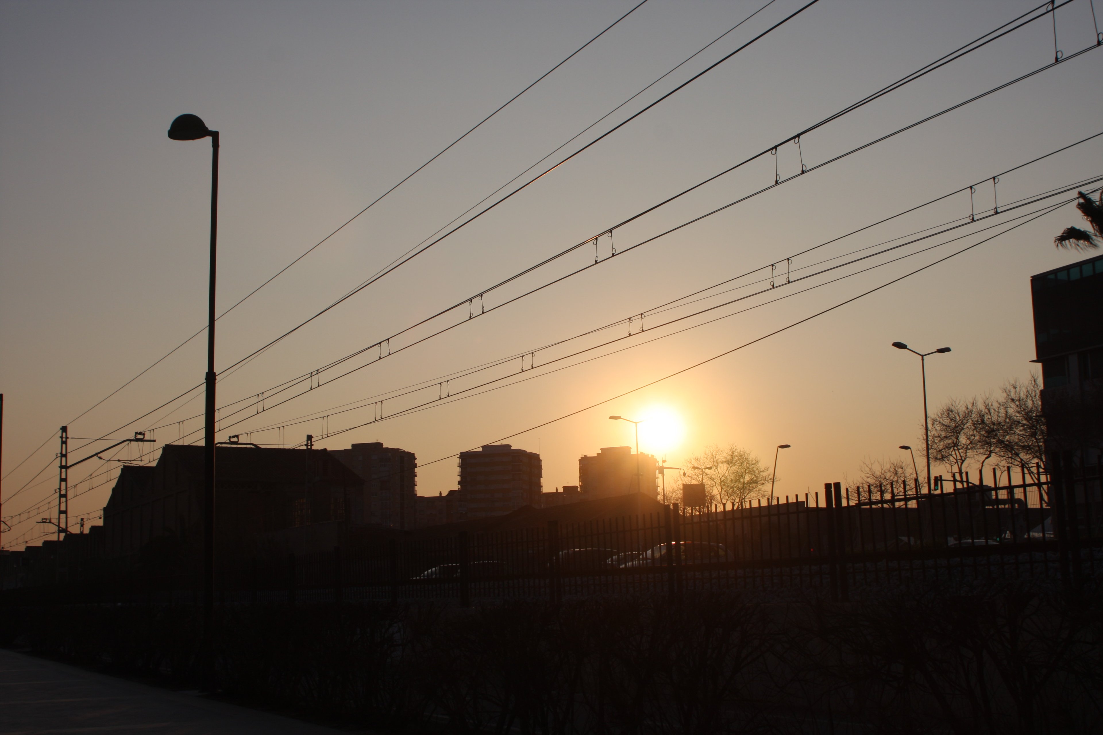 Sunset caught in railway overhead wires above a town silhouette