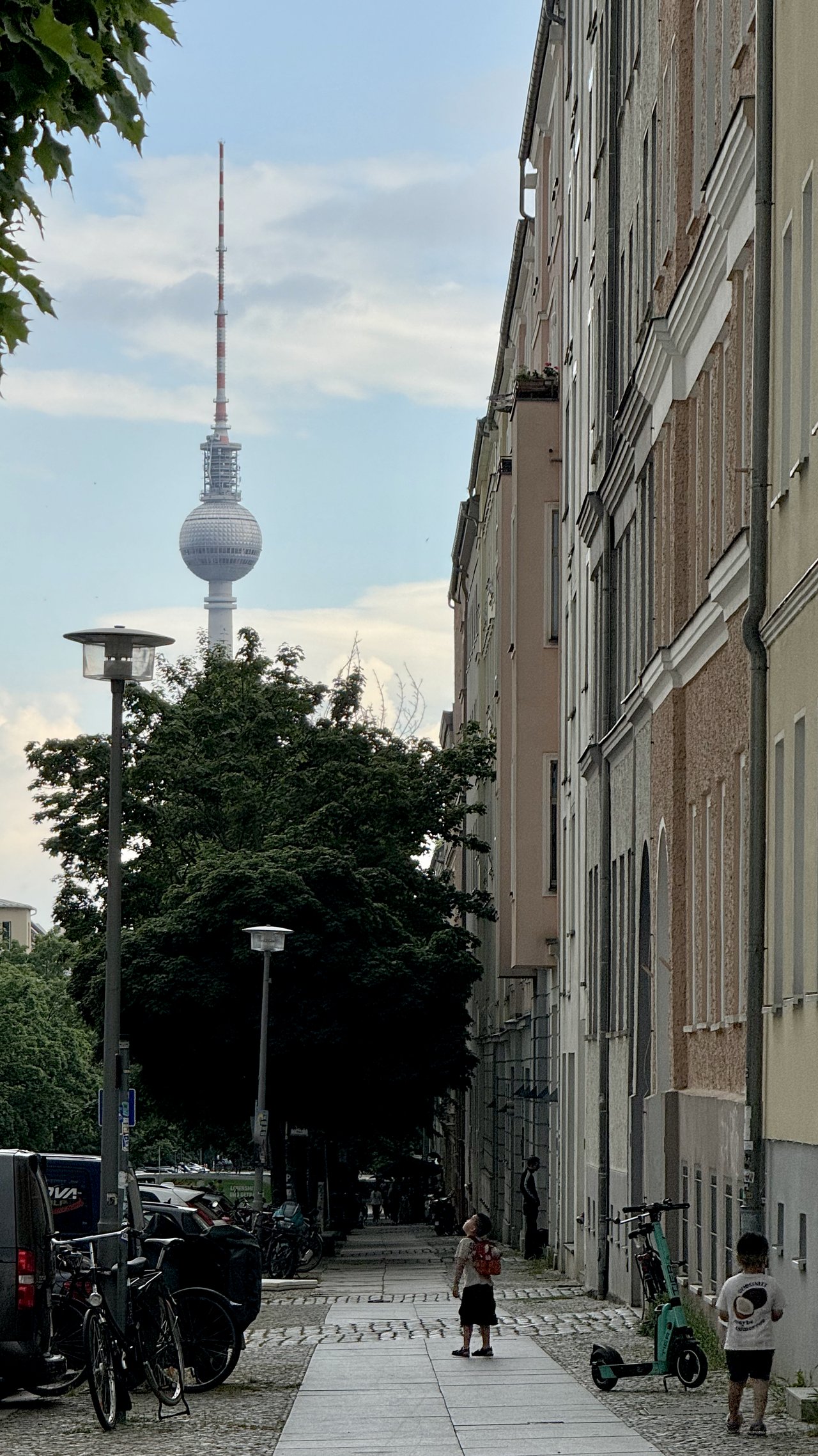 A child looks up a Berlin side street toward the television tower