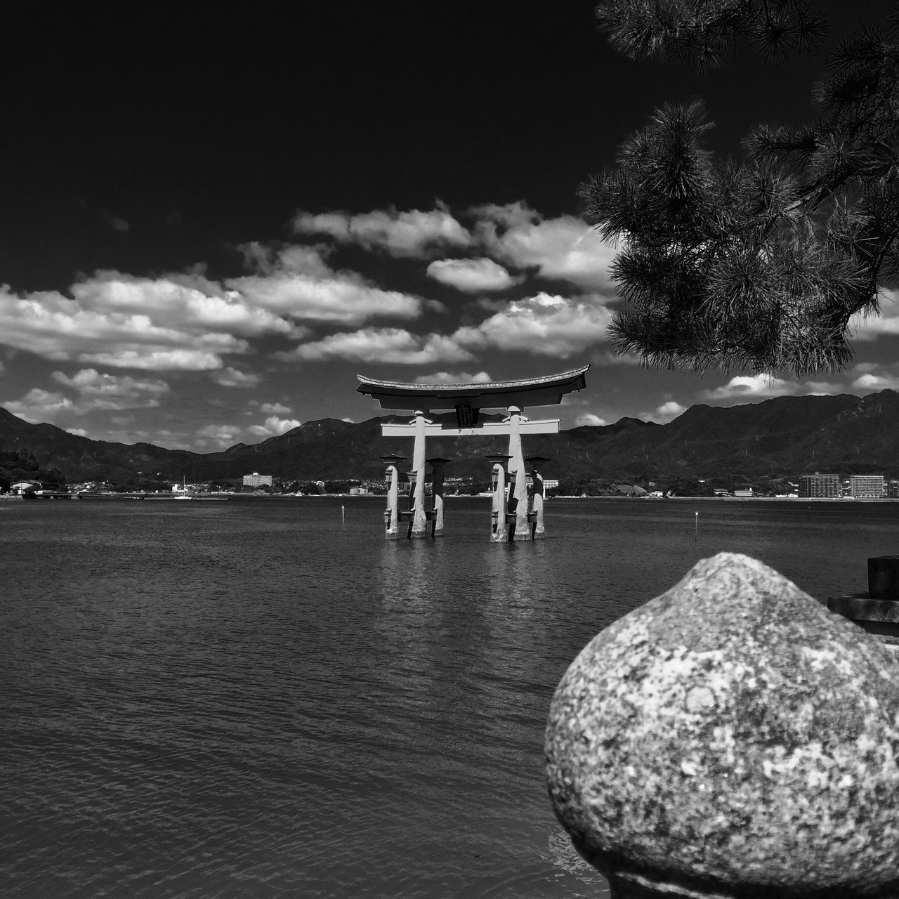 Great torii standing in shallow water, mountains beyond, monochrome
