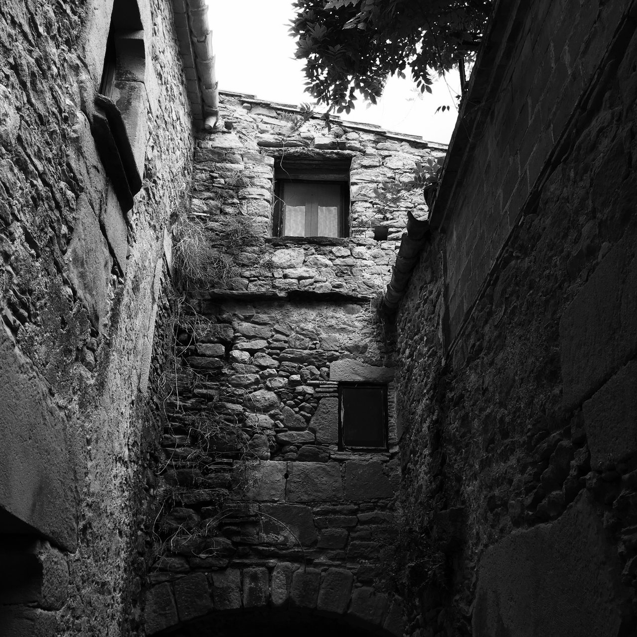 Narrow stone lane between old walls in Rupit, monochrome
