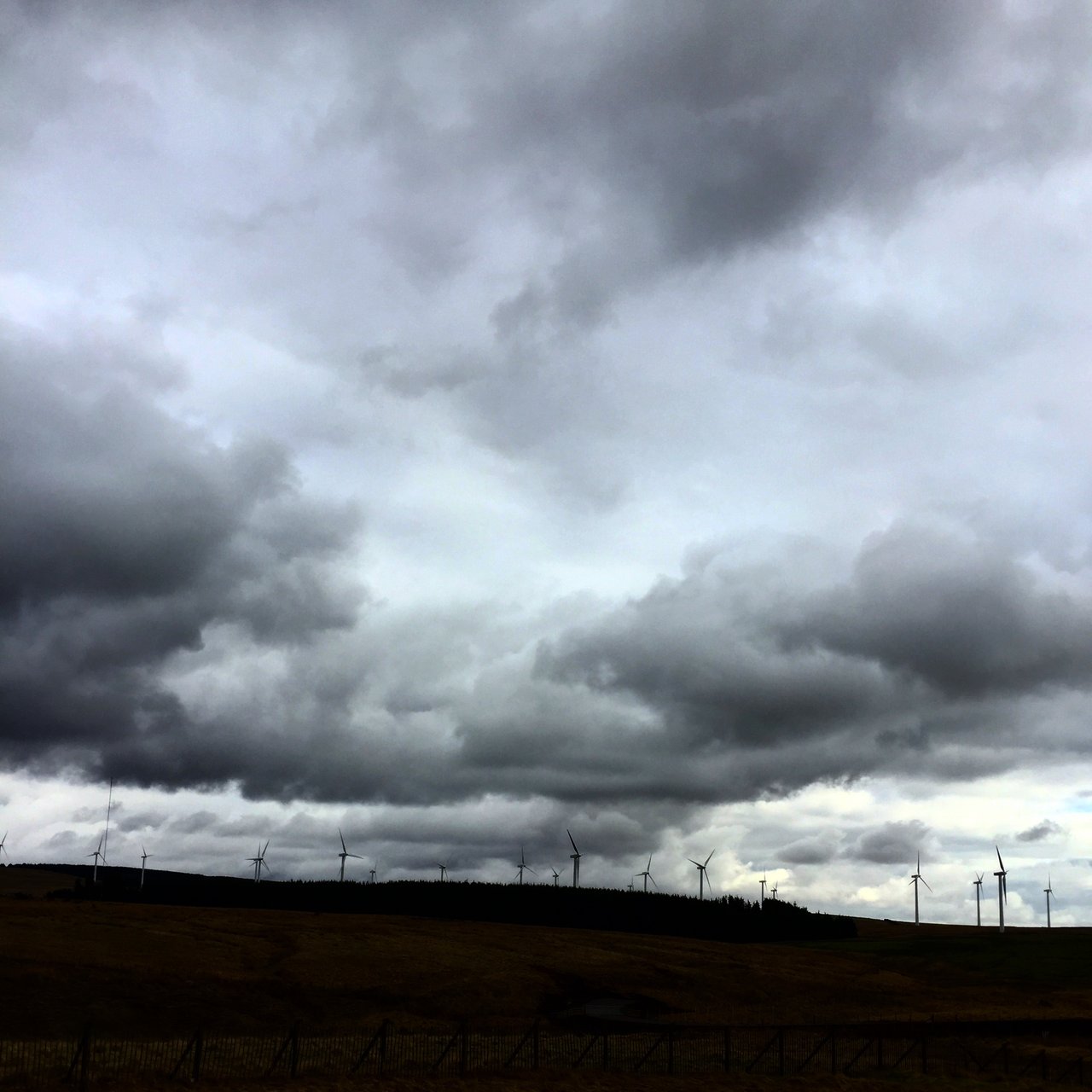 Heavy storm cloud over a ridge line of wind turbines