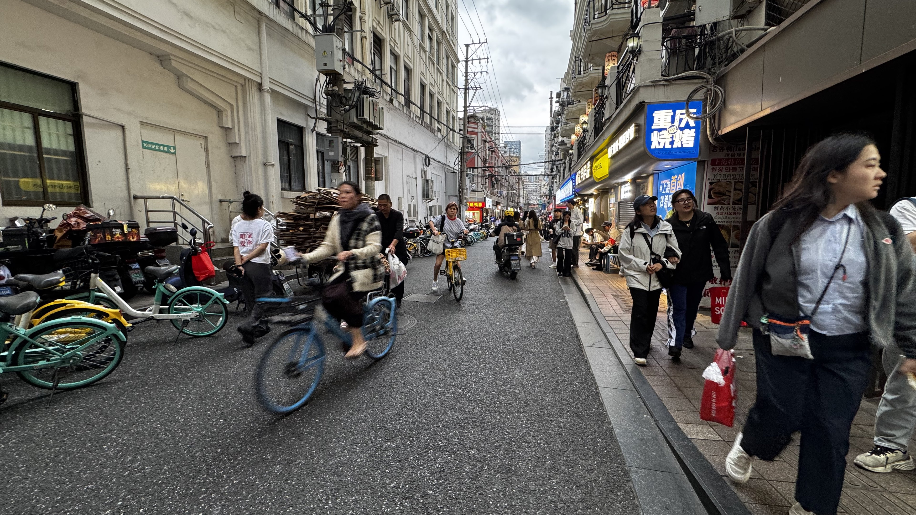 A cyclist hauls a stack of flattened cardboard along a Shanghai lane