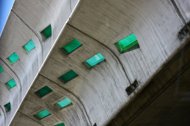 Concrete underpass ceiling pierced by rows of green glass skylights
