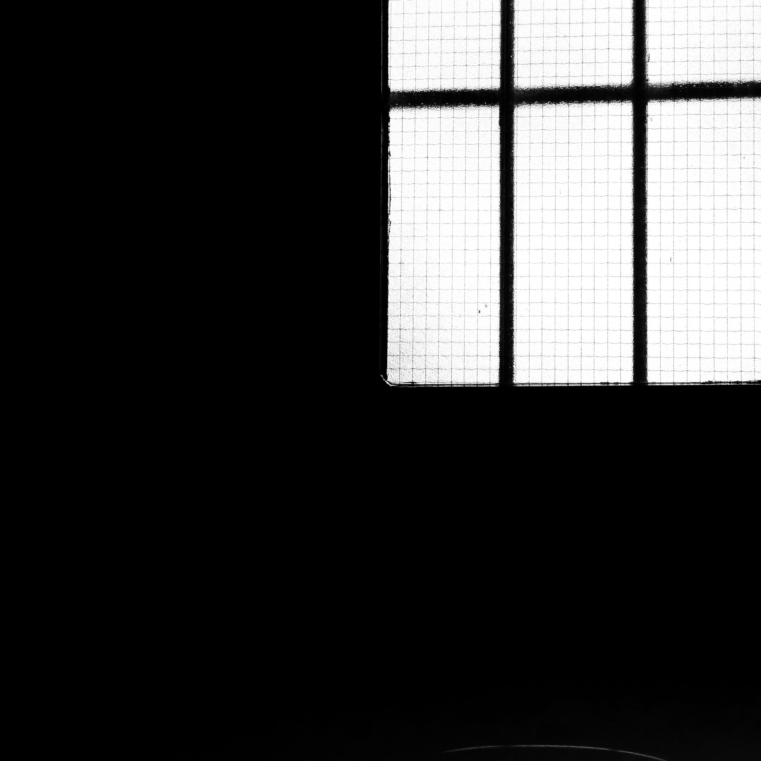 The corner of a wired-glass window in a dark stairwell