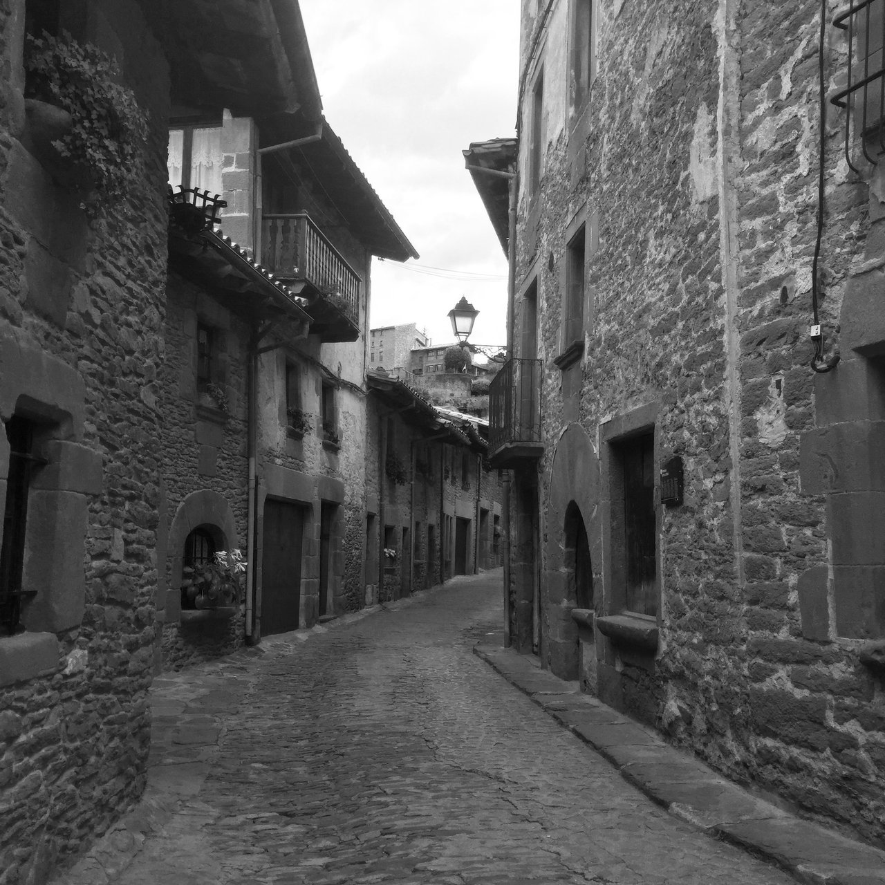 Narrow medieval street of stone houses in Rupit, monochrome