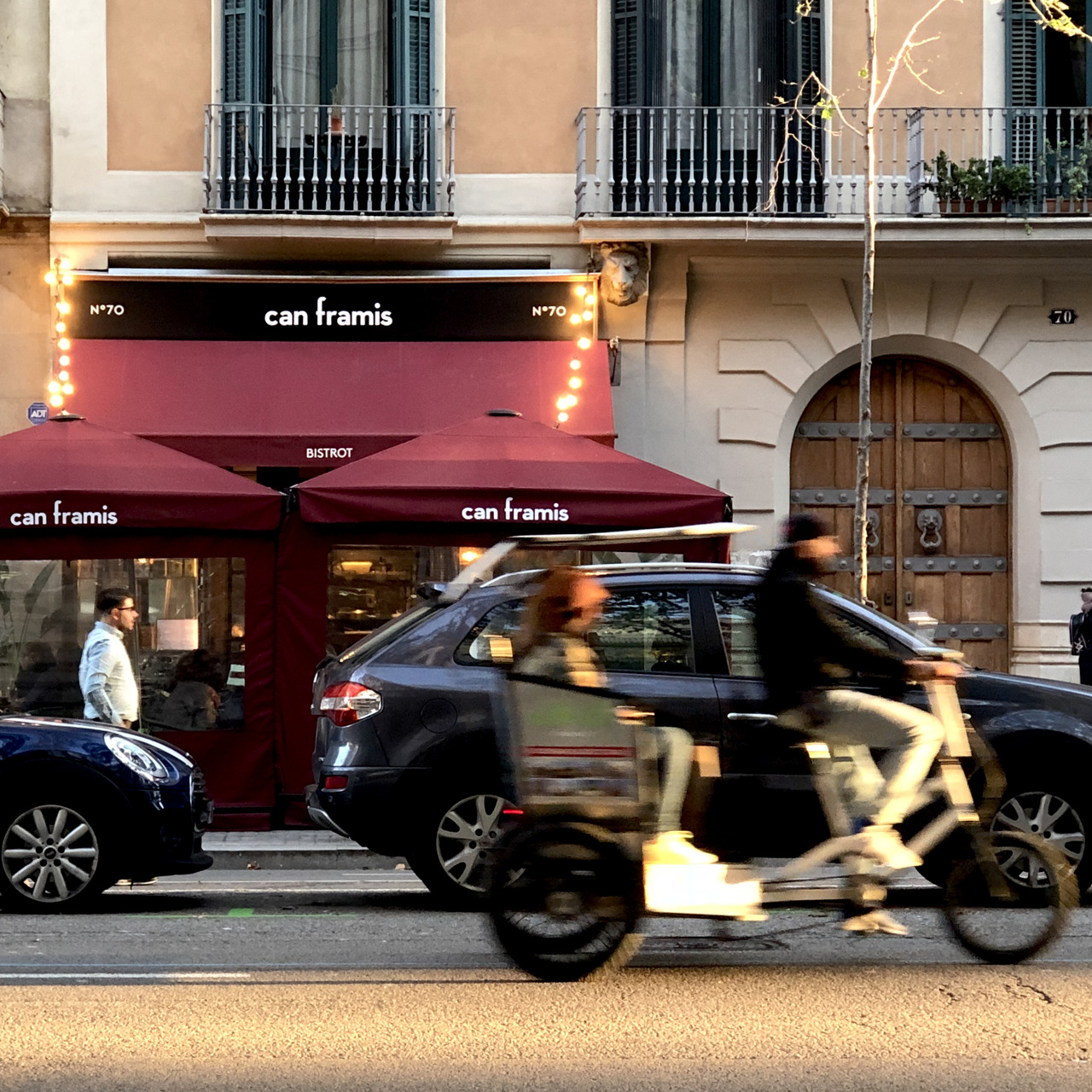 A scooter rider blurs past the Can Framis bistrot awnings at dusk