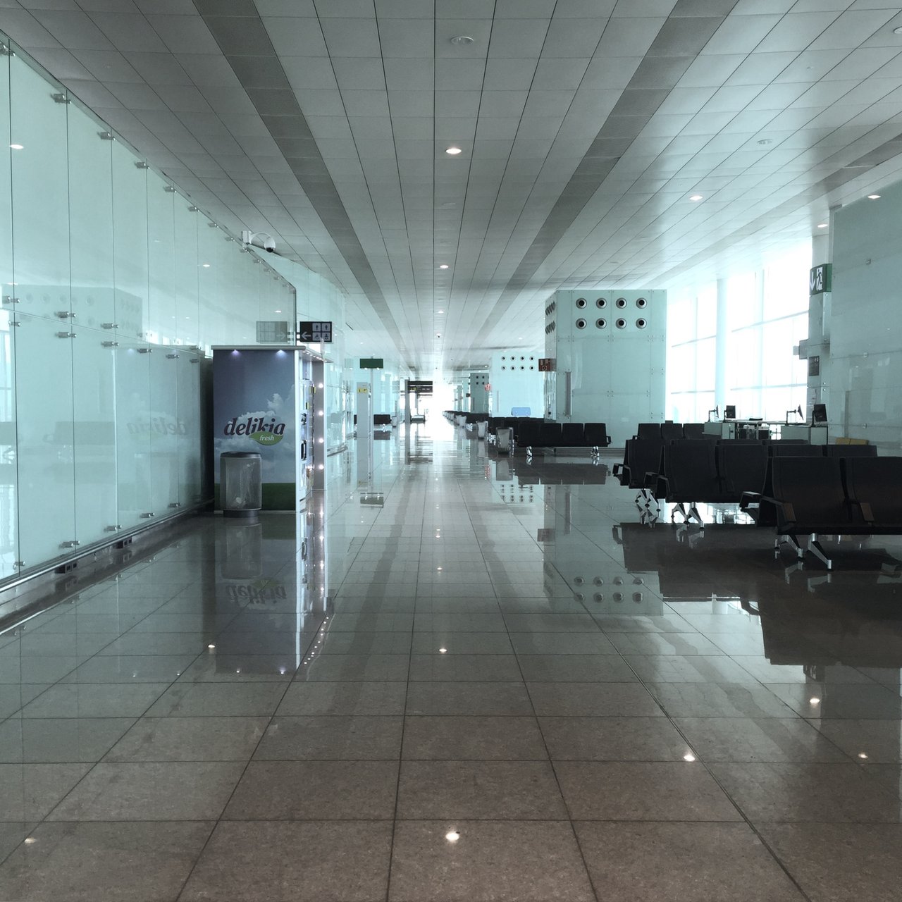 Empty airport corridor, glass wall and polished floor receding to light