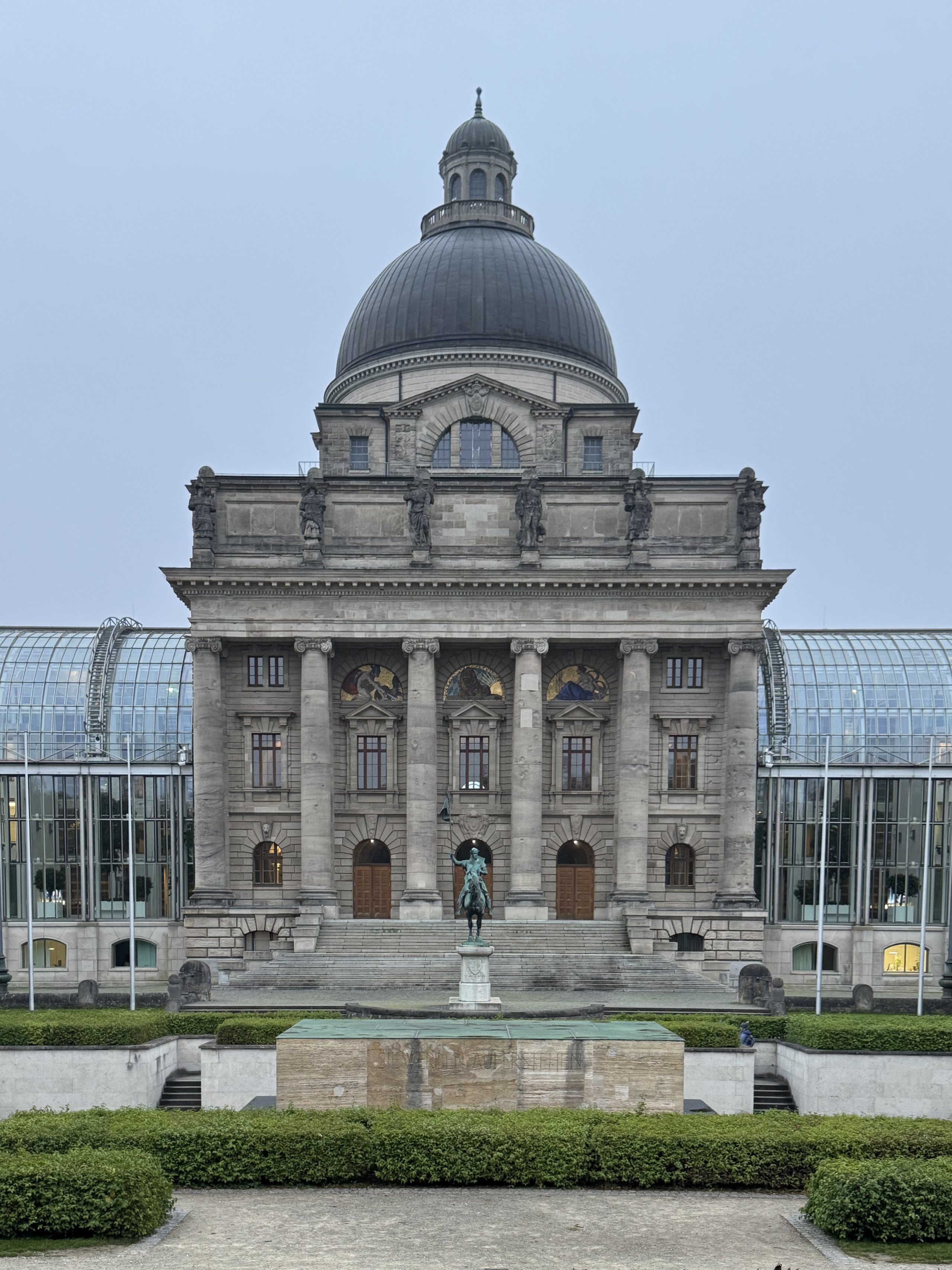 The domed Bavarian State Chancellery between its glass wings at dusk