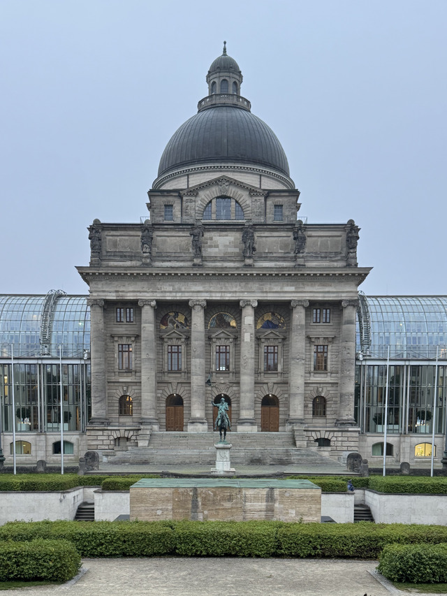 The domed Bavarian State Chancellery between its glass wings at dusk
