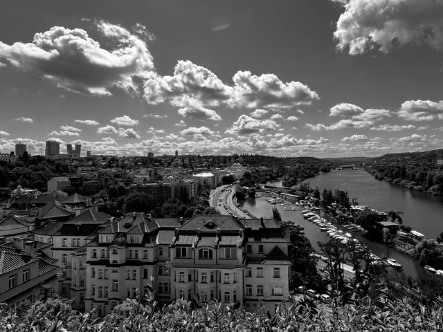 Cumulus clouds over Prague from Vyšehrad, the Vltava bending past a marina of small boats, apartment blocks in the foreground and towers on the horizon