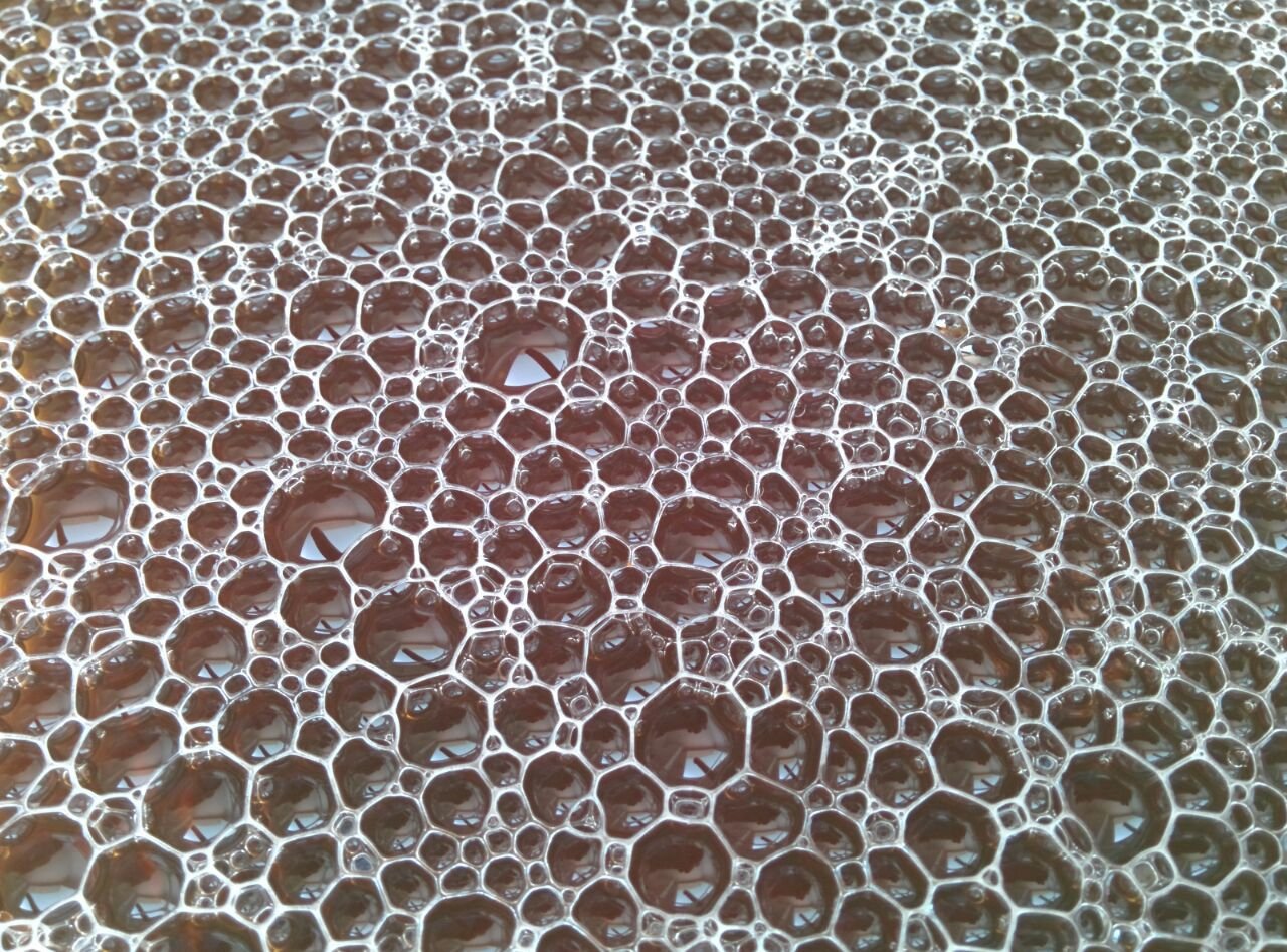 Close-up of foam bubbles, a honeycomb of thin films in warm light