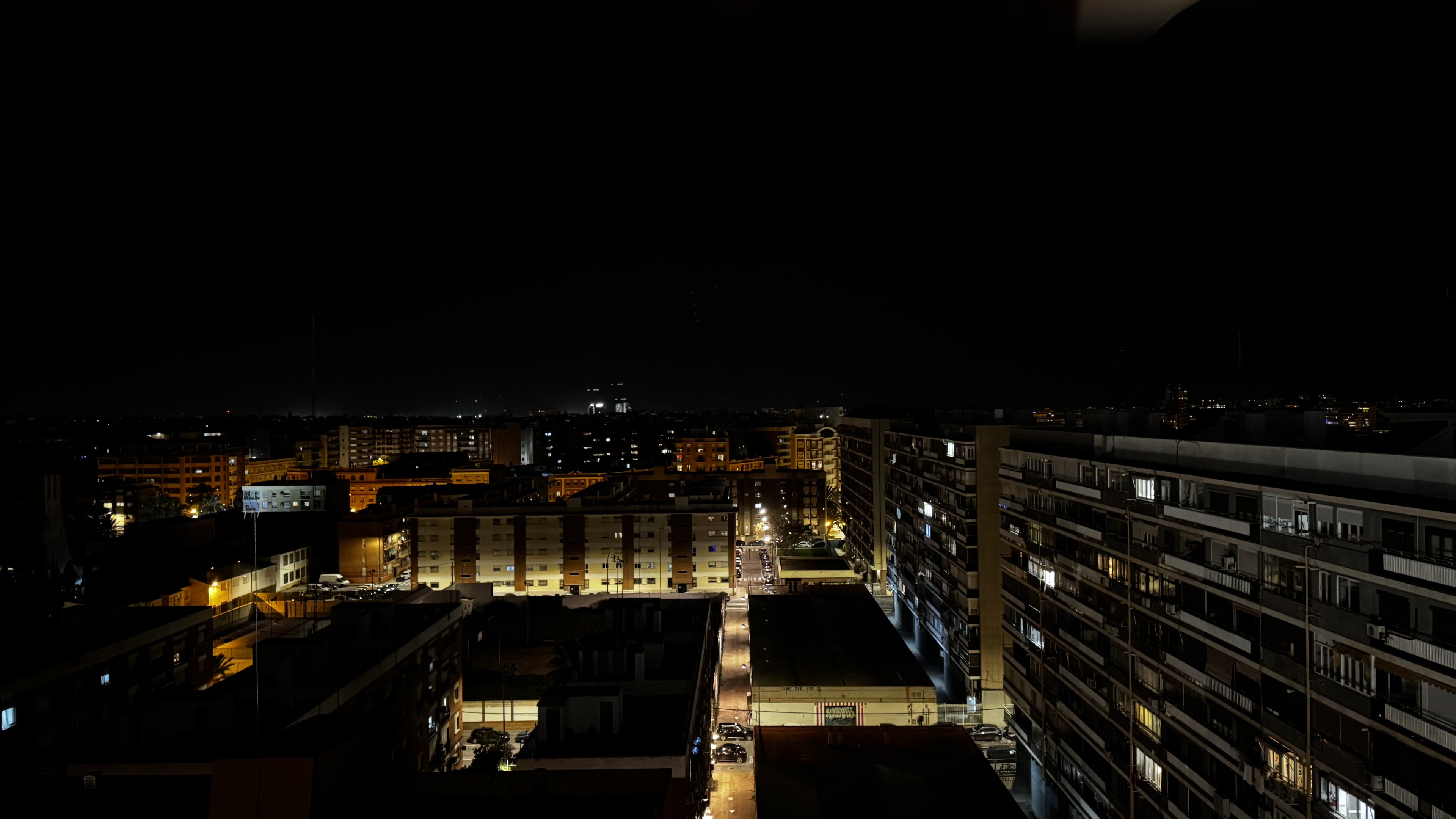 Apartment blocks under sodium light, the city dim to the horizon