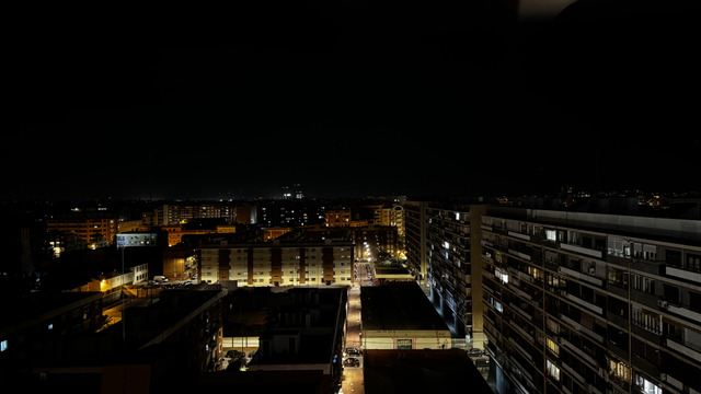 Apartment blocks under sodium light, the city dim to the horizon