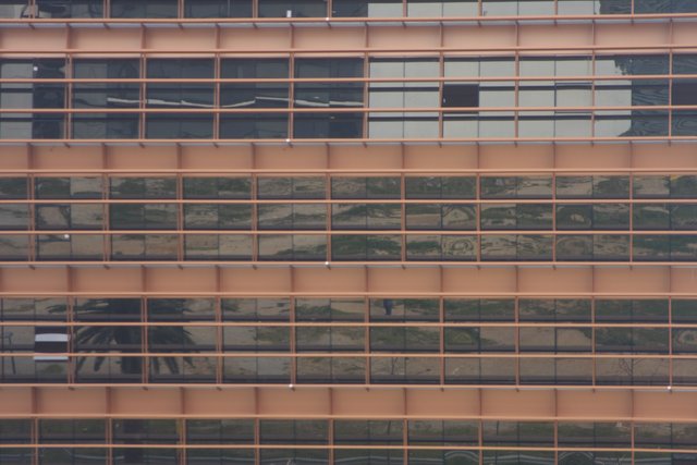 A glass office facade in horizontal bands, reflecting a pink evening sky