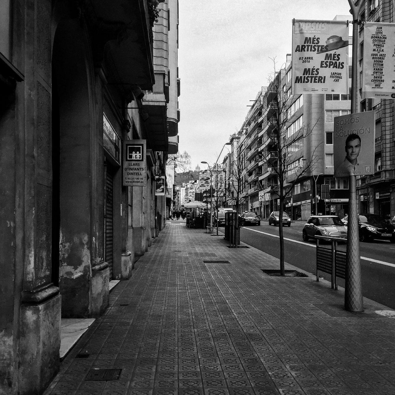 Barcelona street in monochrome, poster hoardings above parked cars