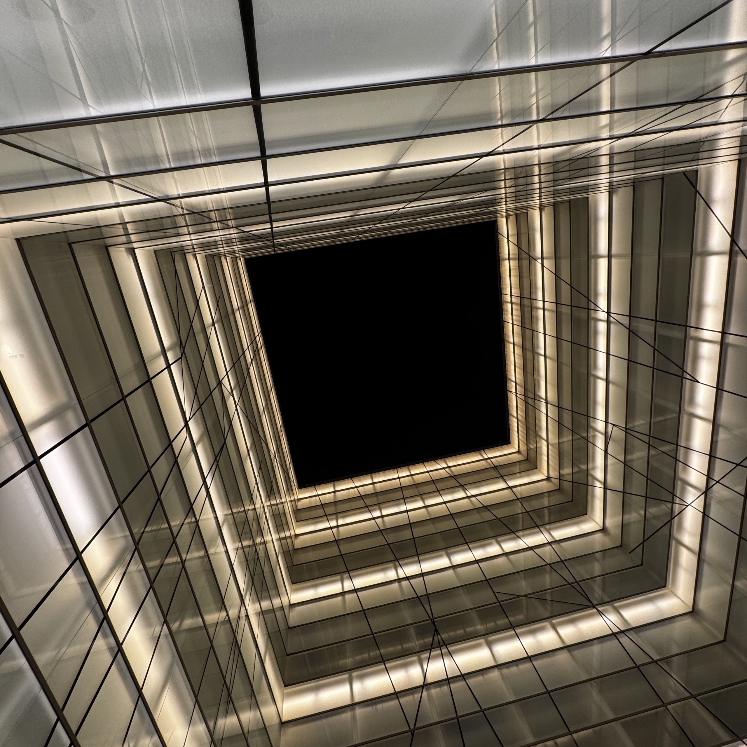 Nested squares of light recede toward a dark skylight, threads crossing the frames