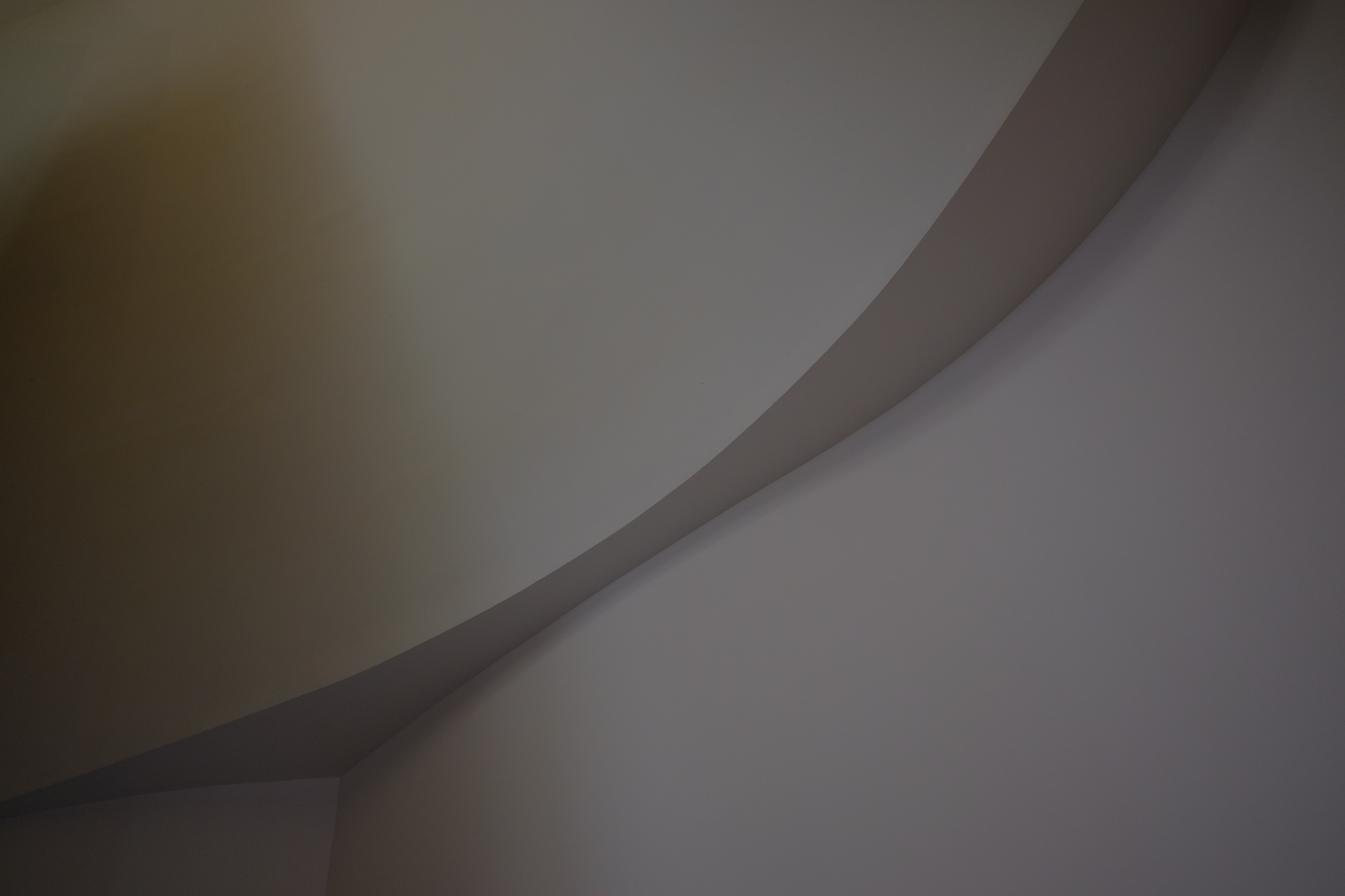 A pale plaster curve narrows to its waist where two walls meet in low light